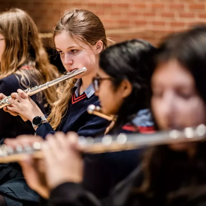 5 girls playing the flute in a music group practice